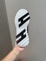 Suola di sneaker moderna con logo stilizzato e design antiscivolo, tenuta in mano.