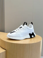 Sneaker bianca moderna con dettagli neri su piedistallo in legno, stile minimalista e di tendenza.