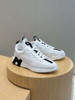 Sneakers bianche moderne con dettagli neri su pedana in legno, stile e comfort trendy.