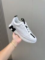 Sneaker bianca e nera minimalista con suola testurizzata, versatile e sportiva per ogni occasione.