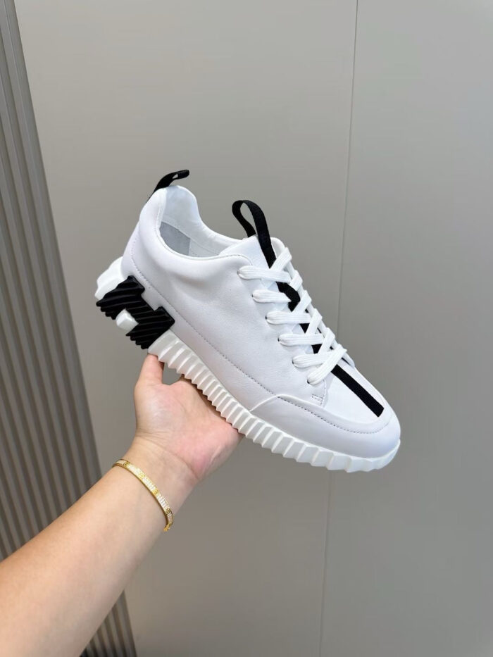 Sneaker bianca e nera minimalista con suola testurizzata, versatile e sportiva per ogni occasione.