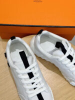 Sneakers bianche di lusso con suola resistente, packaging arancione elegante, stile moderno e confortevole
