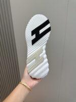 Suola di sneaker bianca con dettagli colorati e design moderno, mostrata in mano contro sfondo semplice.