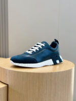 Sneaker moderna in navy blue con suola bianca, su pedestal di legno, stile elegante e sportivo.