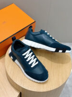 Sneakers eleganti navy con lacci bianchi e suola bianca aderente, in cornice di box arancione understyle.