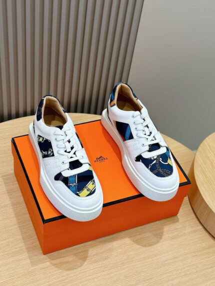 Sneaker di lusso bianche con dettagli colorati su scatola arancione elegante.