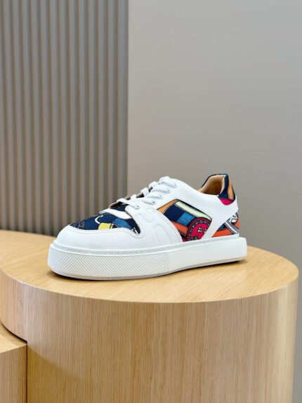 Sneaker moderna con dettagli colorati e suola spessa su pedestal di legno.