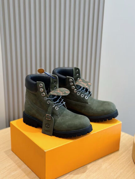 Stivaletti da uomo in suede verde con suola antiscivolo, su scatola arancione brillante.