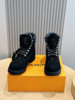 Stivaletti Louis Vuitton in suede nero con packaging di lusso su tavolo in legno.