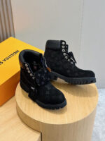 Stivaletti in suede Louis Vuitton con dettagli moderni e eleganti, su piedistallo di legno.