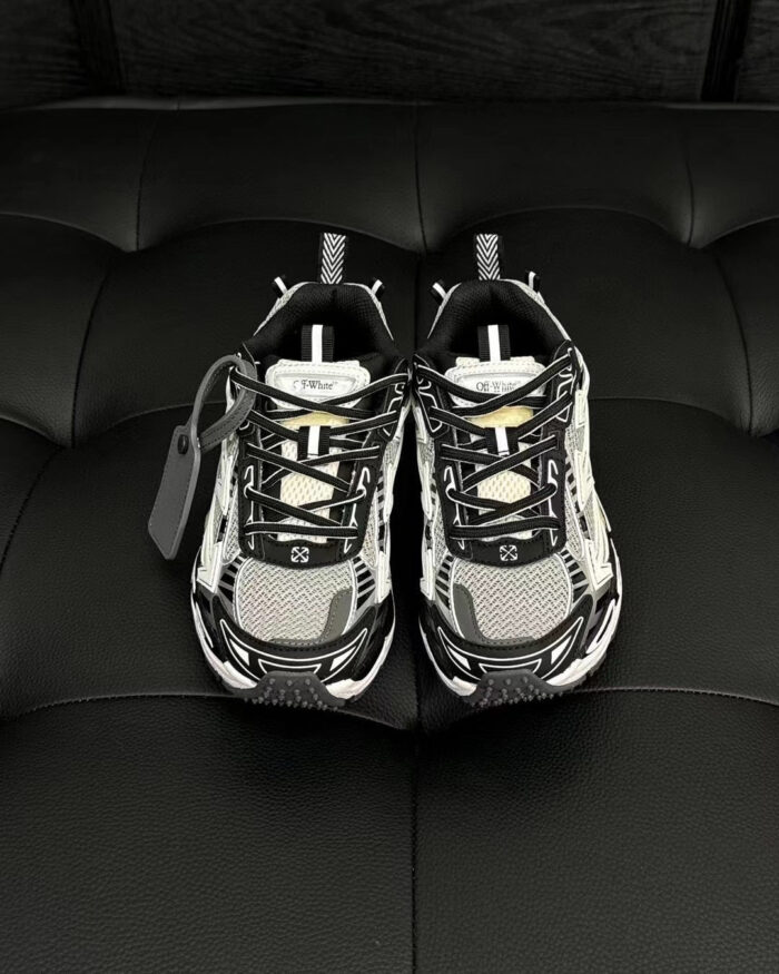 Scarpe sportive moderne nere e bianche con dettagli grigi e suola antiscivolo elegante.