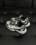 Scarpe sportive moderne nere e silver su superficie nera, eleganti e performanti.