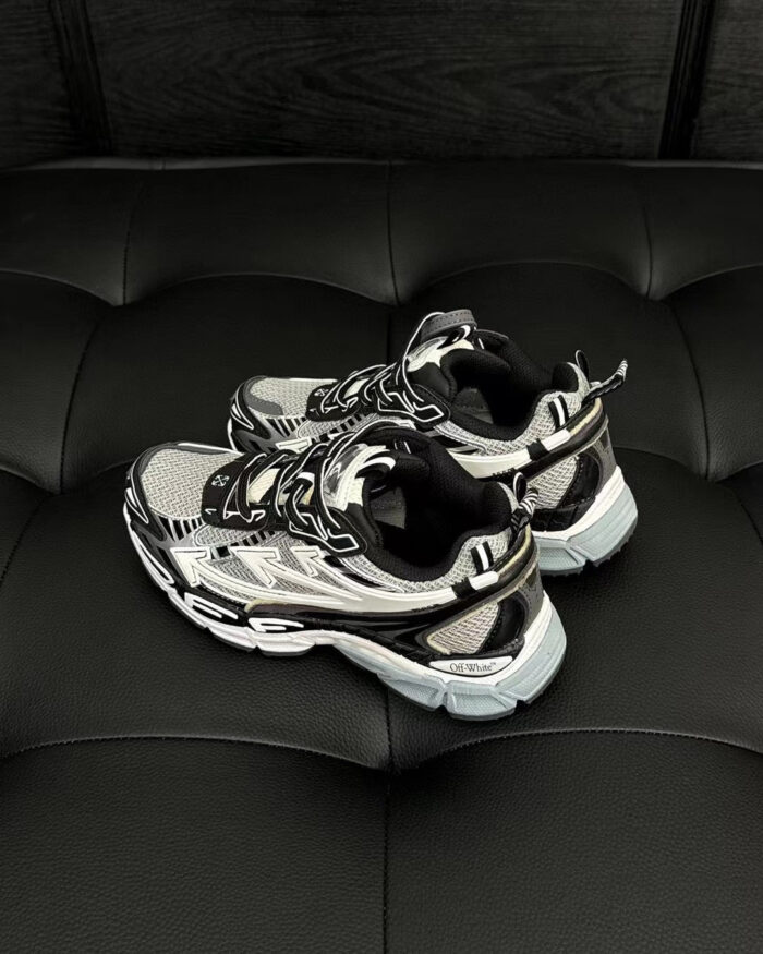 Scarpe sportive moderne nere e silver su superficie nera, eleganti e performanti.