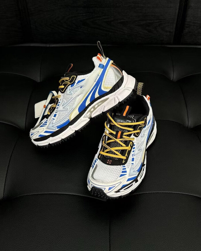 Scarpe da corsa bianche con dettagli blu, arancioni e gialli su sfondo nero elegante.
