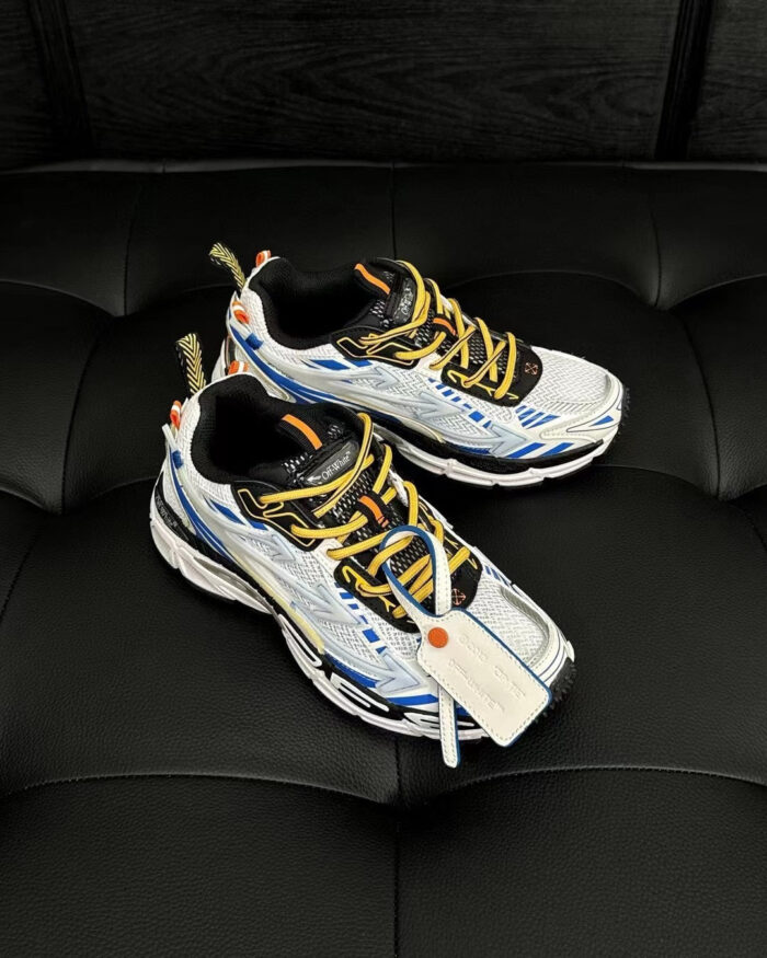 Sneakers sportive bianche con dettagli blu, arancioni e lacci gialli, comode e di tendenza.