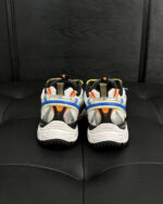 Scarpe sportive bianche con dettagli arancioni e blu, design moderno e performance elevata.