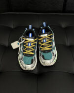 Sneakers futuristiche colorate con dettagli moderni e finiture lucide su sfondo scuro e tufted.