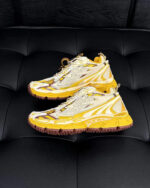 Scarpe sportive futuristiche gialle e bianche con suola antiscivolo su superficie nera lucida.