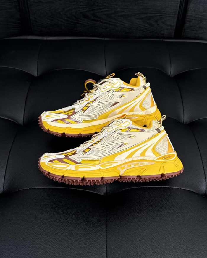 Scarpe sportive futuristiche gialle e bianche con suola antiscivolo su superficie nera lucida.