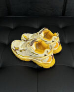 Sneakers bianche con dettagli gialli su superficie nera eleganti, stile sportivo e moderno.