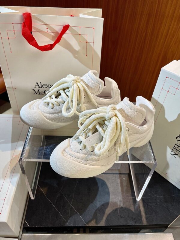 Sneakers di lusso bianche con dettagli eleganti, in esposizione con borse alla moda.