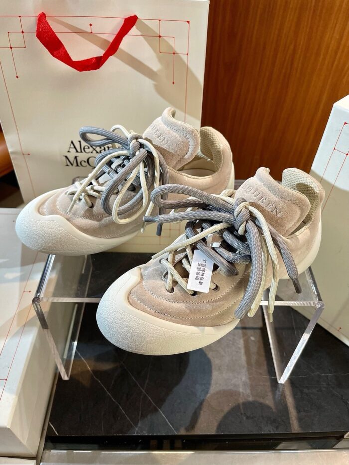 Scarpe Alexander McQueen in suede beige, design elegante e modern, su supporto trasparente.