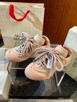 Sneakers rosa pastello di lusso Alexander McQueen su supporto di vetro in boutique elegante.