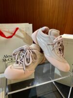 Scarpe sportive rosa di lusso Alexander McQueen su sfondo elegante e packaging esclusivo