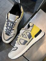 Sneaker beige con dettagli gialli e grigi, stile casual e sportivo, comoda e moderna.