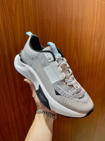 Sneaker moderna in mesh grigio con dettagli colorati e suola spessa, stile casual e trendy.