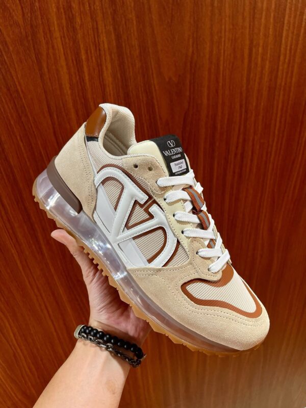 Sneaker di lusso in suede beige, dettagli marroni e suola trasparente con aria ammortizzante.