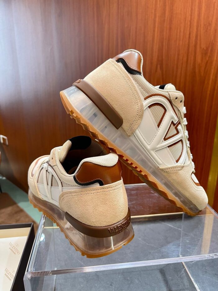 Sneaker da uomo beige e marrone con logo distintivo e suola trasparente in stile moderno.