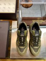 Sneakers di lusso Valentino su superficie di vetro in ambiente raffinato.