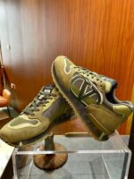 Sneakers di lusso verdi moderne su stand trasparente, design elegante e materiali di alta qualità.