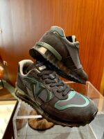 Sneakers moderne in mesh e suede con dettagli teal, eleganti e trendy su sfondo in legno.