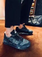 Sneakers nere moderne con pantaloni tagliati e borsa di lusso, stile elegante e casual.