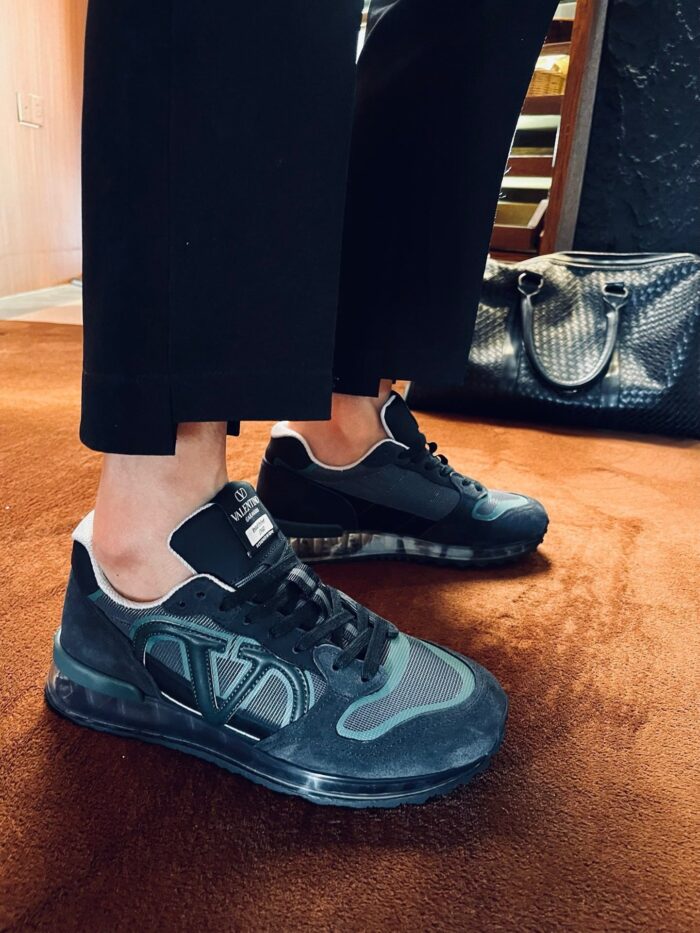 Sneakers nere moderne con pantaloni tagliati e borsa di lusso, stile elegante e casual.