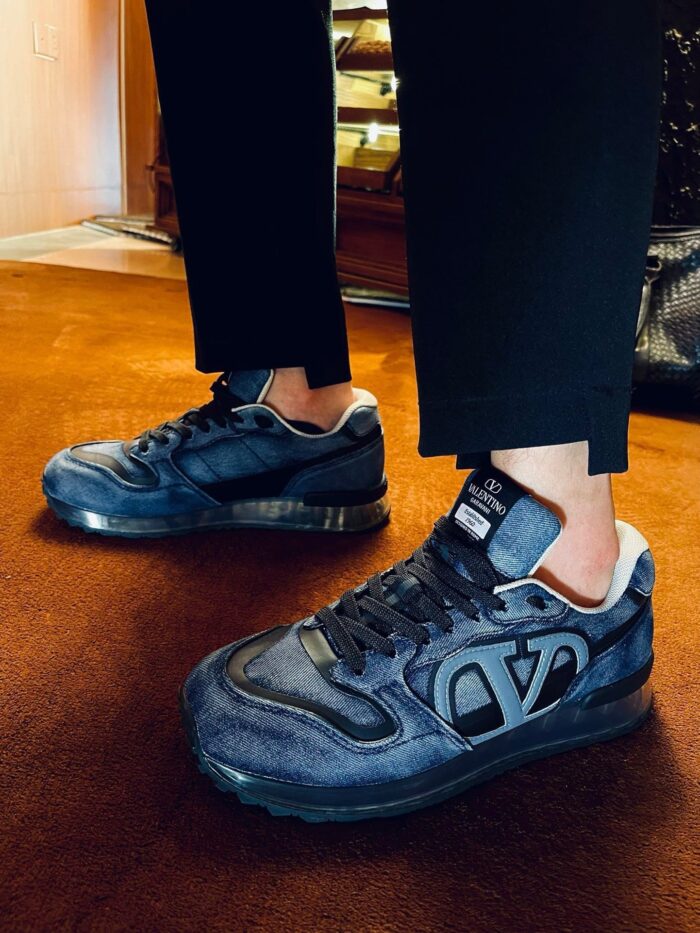 Sneaker nere moderne con pantaloni cropped in ambiente elegante e soffice tappeto.