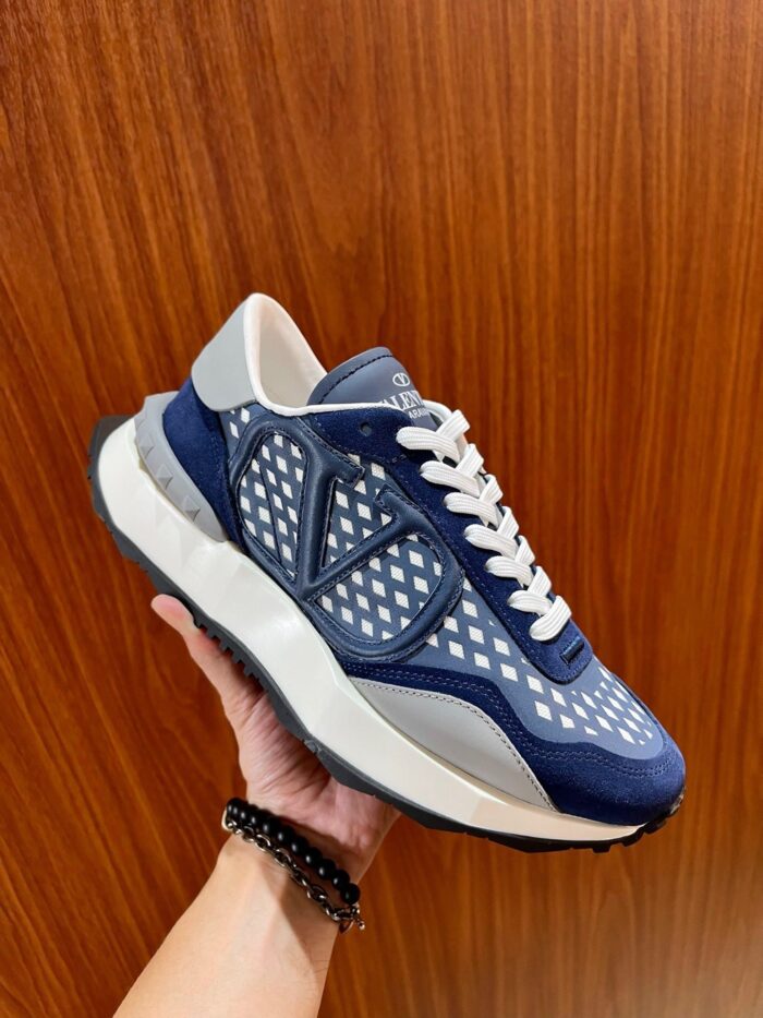 Sneaker moderna blu navy con dettagli geometrici, su sfondo in legno caldo.