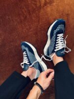 Scarpe sportive navy eleganti con perforazioni, su sfondo caldo e dettagli di stile moderno.