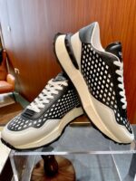 Sneakers moderne nero bianco con design essenziale e su supporto in vetro elegante.