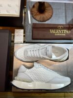 Sneaker Valentino Garavani di design moderno su superficie riflettente, ambiente di lusso e alta moda.