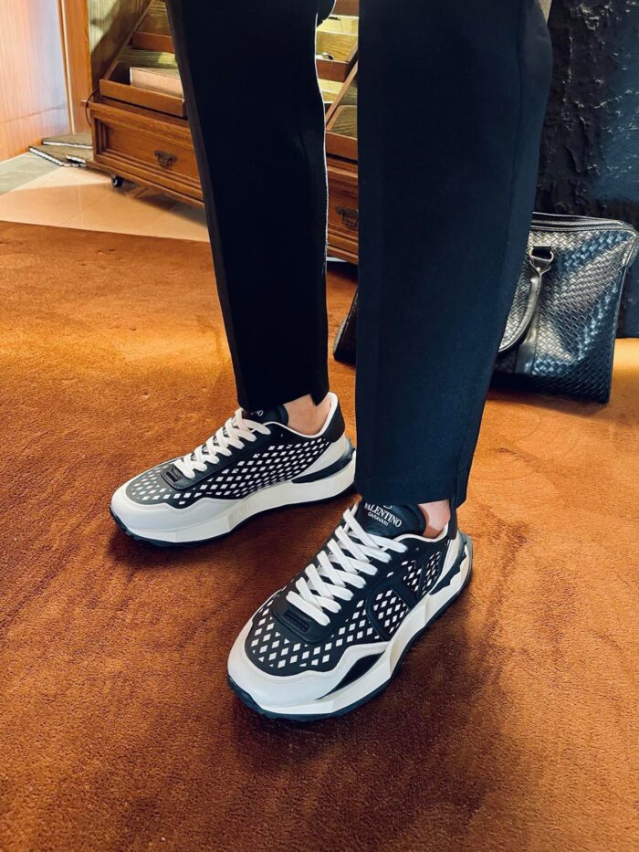 Sneakers nere moderne con dettagli bianchi, pantaloni slim e ambiente elegante, stile casual-chic.