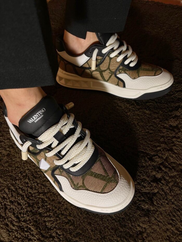 Sneakers camouflage moderne in pelle e tessuto, stile streetwear elegante con suola bianca resistente.