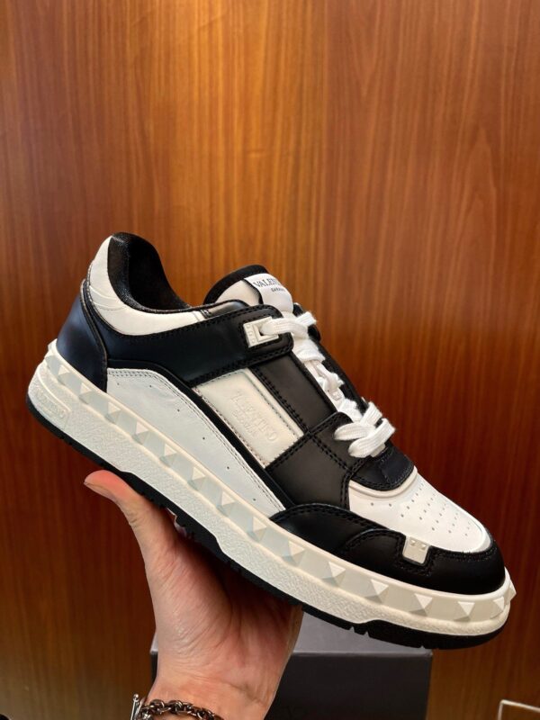 Sneaker moderna nera e bianca con suola chunky, stile sportivo e casual elegante.