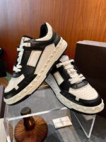 Sneakers moderne in nero, bianco e beige, stile sportivo e design elegante su supporto di plexiglass.