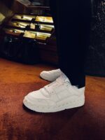 Sneakers bianche moderne con pantaloni neri, stile urbano e contrasto di colori eleganti.