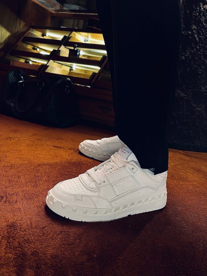 Sneakers bianche moderne con pantaloni neri, stile urbano e contrasto di colori eleganti.