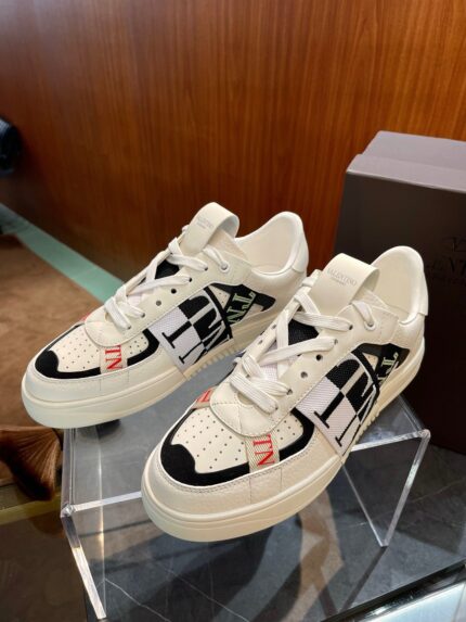 Sneakers moderne bianche con dettagli neri e rossi, stile sportivo e design elegante.