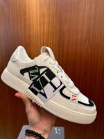 Sneaker bianca moderna con grafiche geometriche, dettaglio verde e stile streetwear elegante.